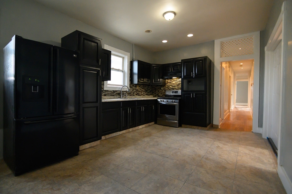 4 Burton Avenue, Unit 3 Boston, MA 02119 - Photo 6 of 17 a kitchen with stainless steel appliances granite countertop a refrigerator and a sink