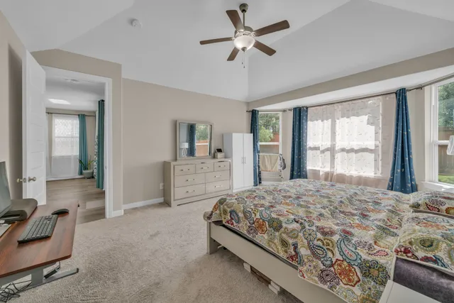 a bedroom with a large bed and a chandelier fan