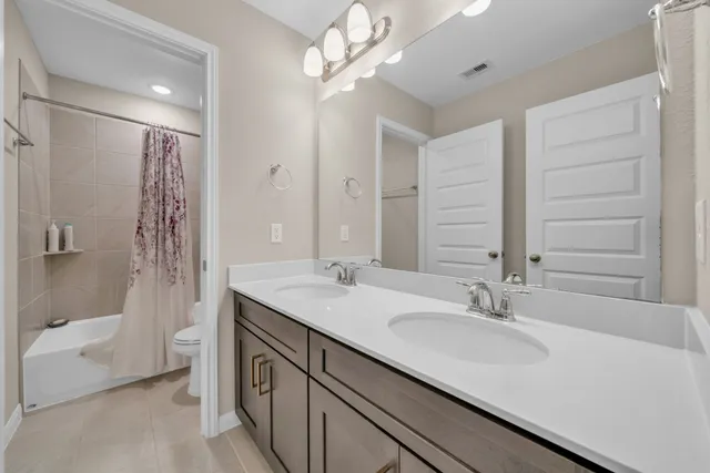 a bathroom with a double vanity sink a toilet and shower