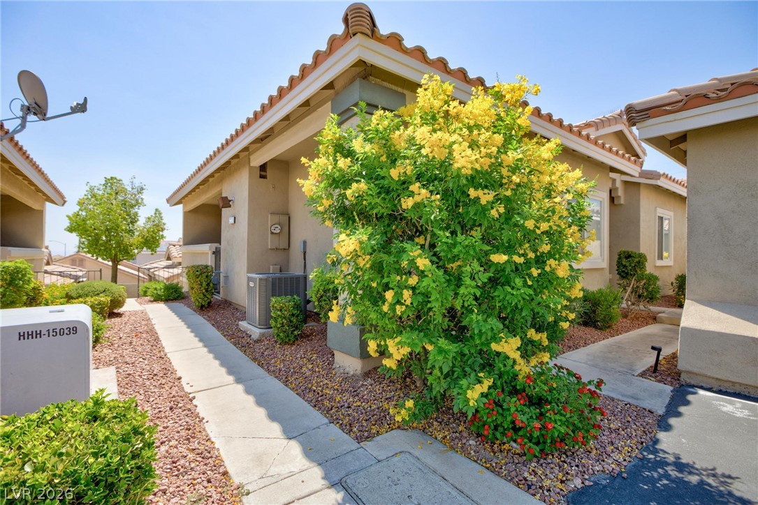 3238 Mystic Ridge Court Las Vegas, NV 89129 - Photo 21 of 31 A terracotta-tiled roof crowns this residence, featuring desert-friendly landscaping with a bright yellow blooming shrub.