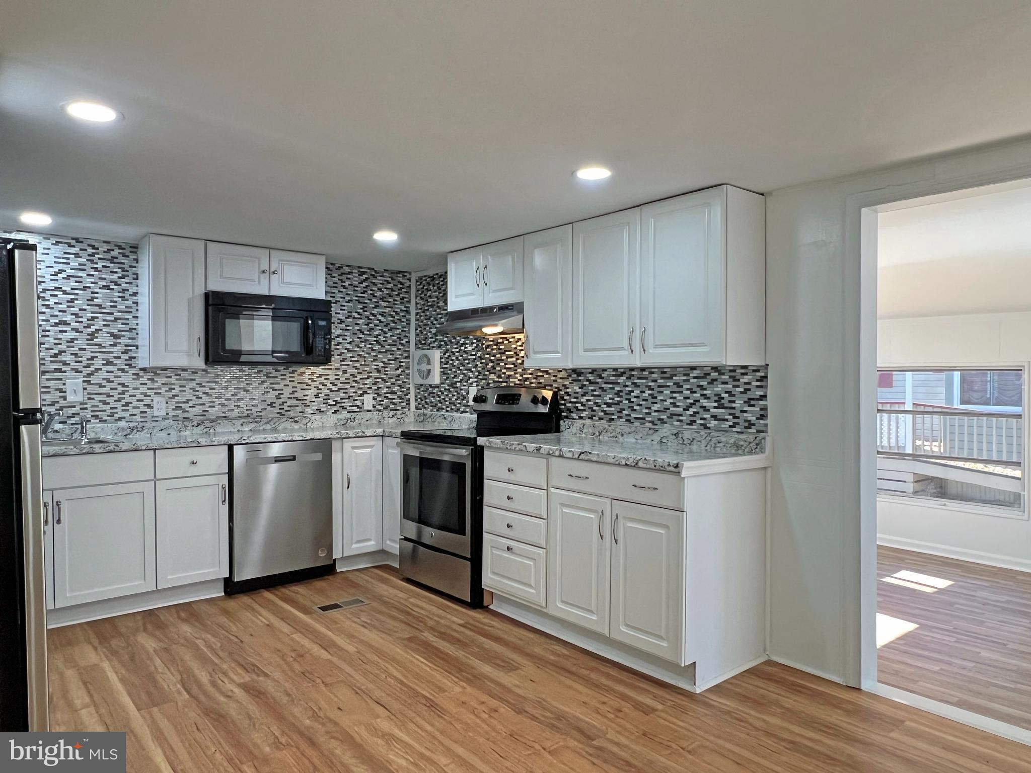31658 Siham Road, Unit E42 Lewes, DE 19958 - Photo 11 of 35 a kitchen with granite countertop white cabinets and white appliances