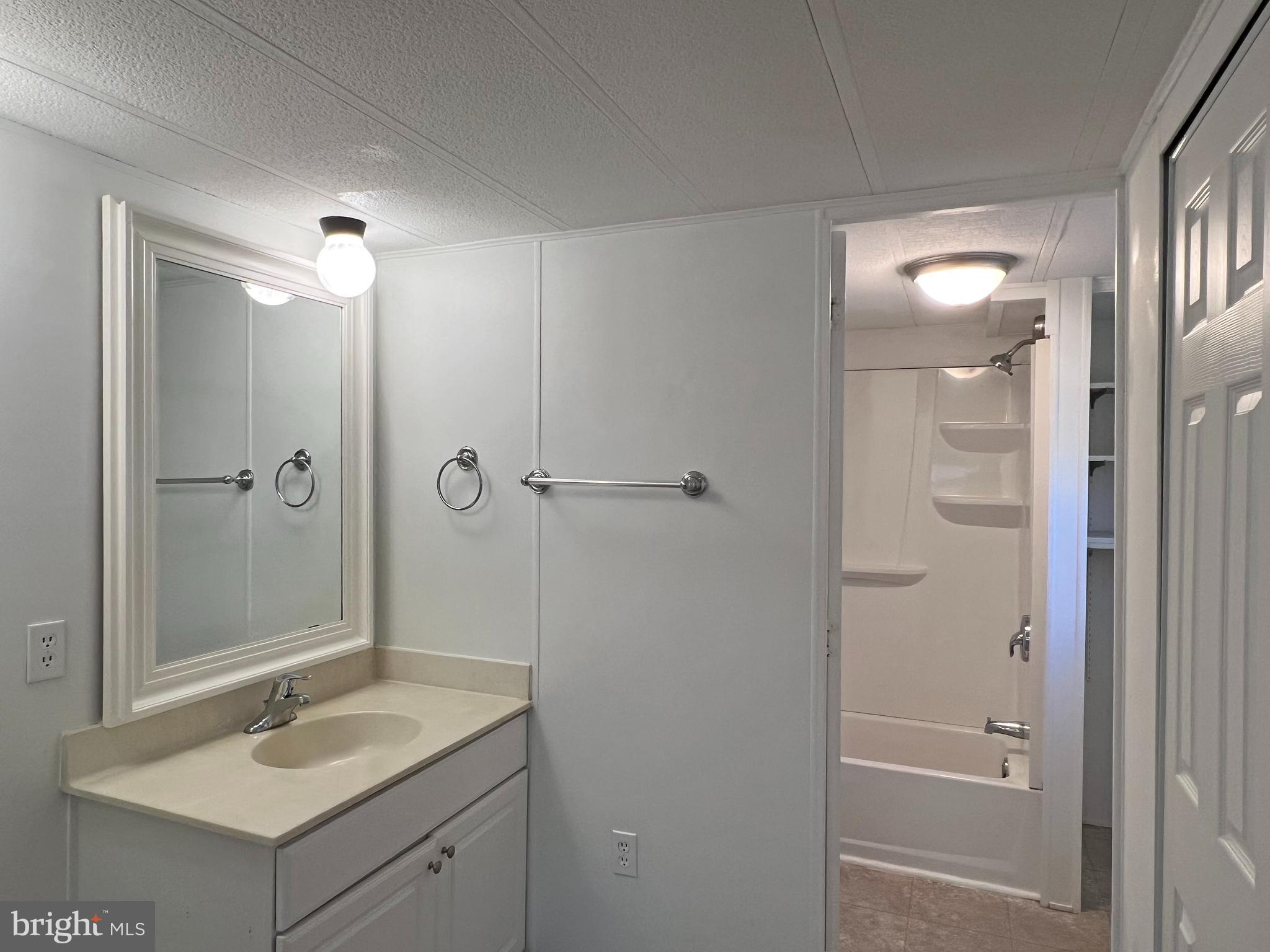 31658 Siham Road, Unit E42 Lewes, DE 19958 - Photo 17 of 35 a bathroom with a granite countertop sink a shower and mirror