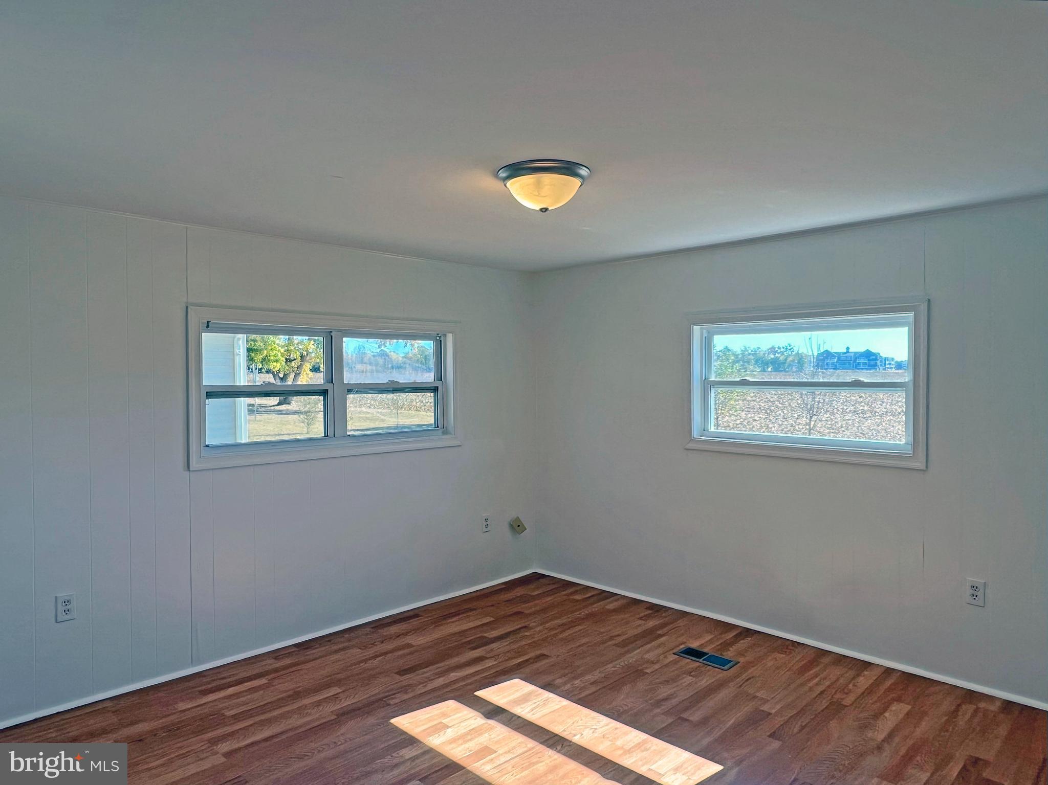 31658 Siham Road, Unit E42 Lewes, DE 19958 - Photo 19 of 35 a view of an empty room with wooden floor and a window