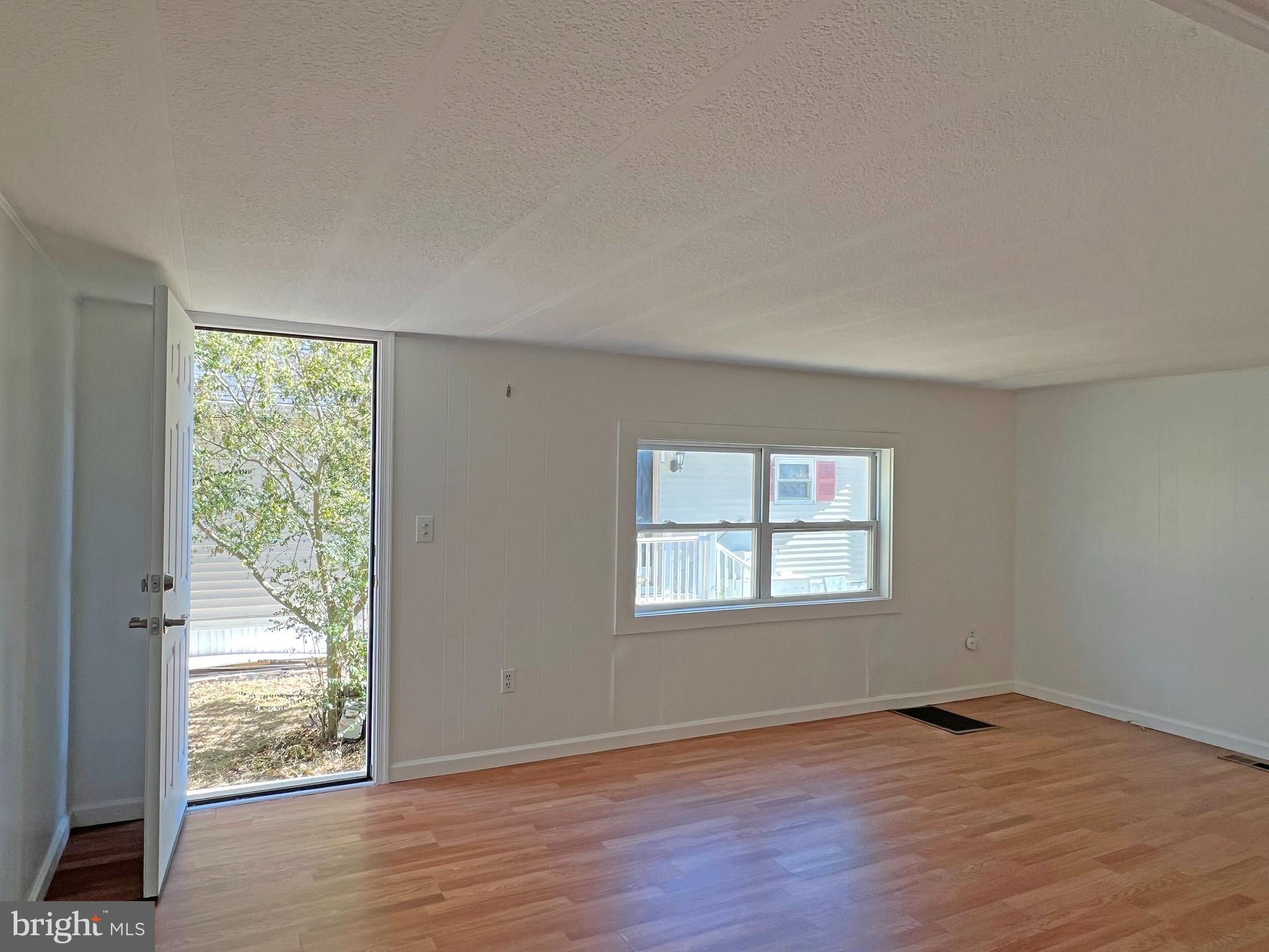 31658 Siham Road, Unit E42 Lewes, DE 19958 - Photo 2 of 35 a view of an empty room with wooden floor and a window