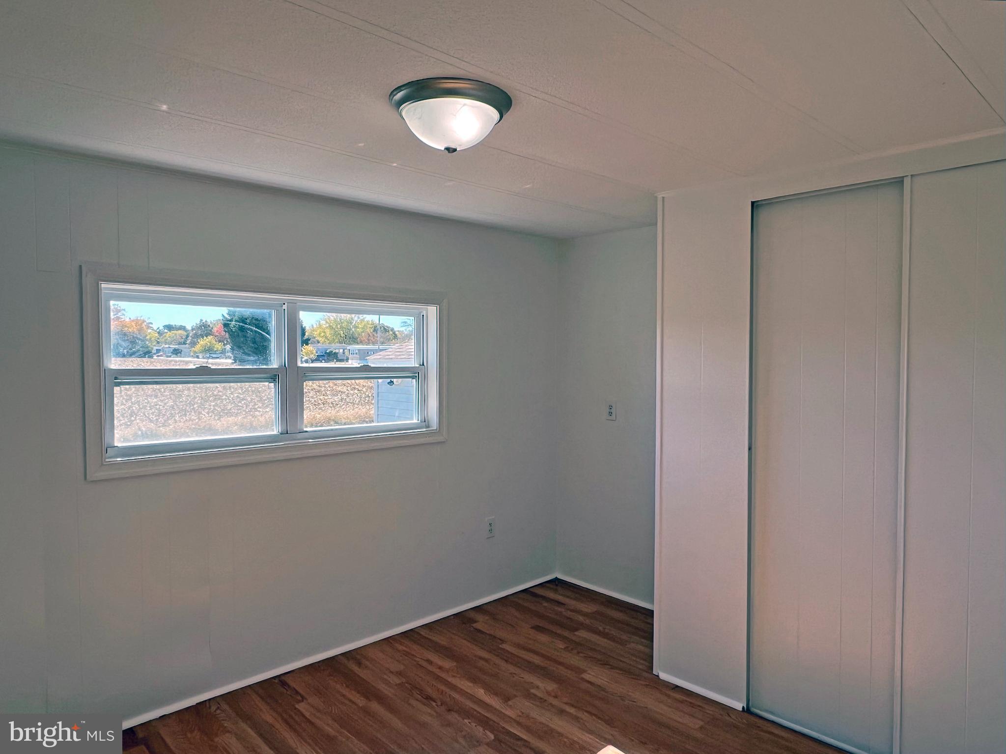 31658 Siham Road, Unit E42 Lewes, DE 19958 - Photo 21 of 35 a view of an empty room with wooden floor and a window