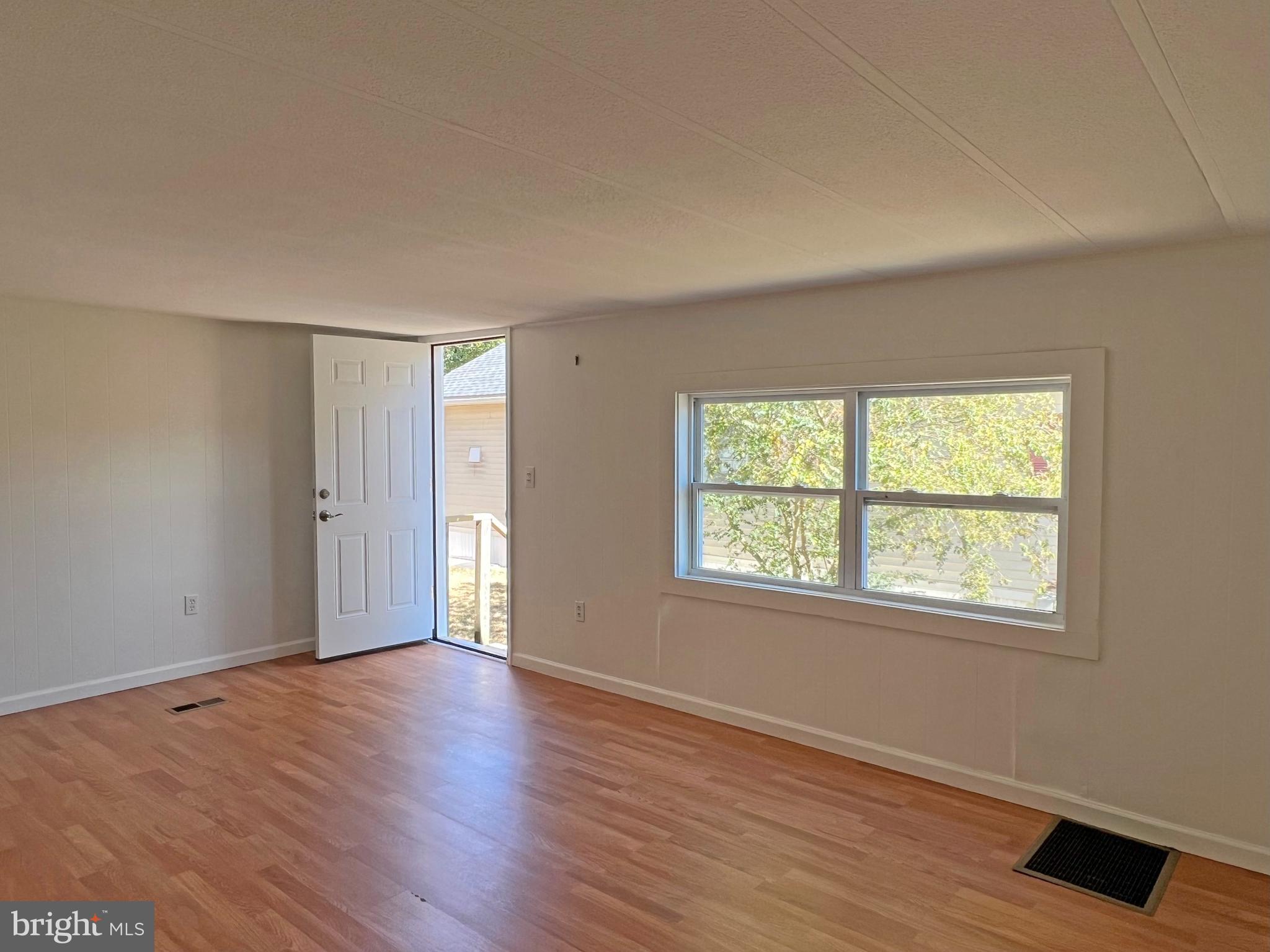 31658 Siham Road, Unit E42 Lewes, DE 19958 - Photo 3 of 35 a view of an empty room with wooden floor and a window
