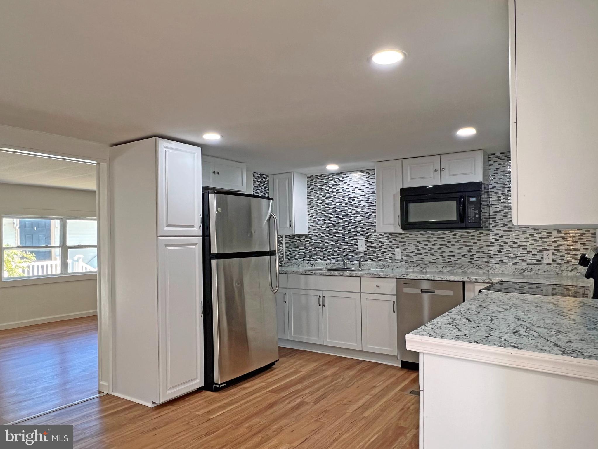 31658 Siham Road, Unit E42 Lewes, DE 19958 - Photo 6 of 35 a kitchen with stainless steel appliances granite countertop a refrigerator and a stove top oven