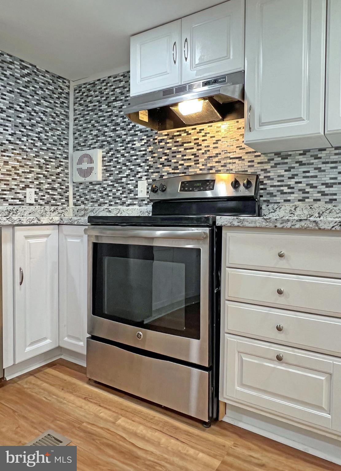 31658 Siham Road, Unit E42 Lewes, DE 19958 - Photo 10 of 35 a kitchen with granite countertop white cabinets and stainless steel appliances