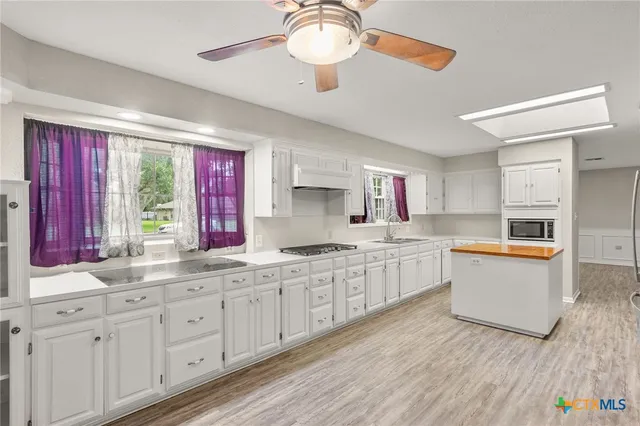 a kitchen with granite countertop white cabinets and window