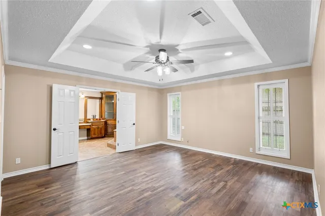 an empty room with wooden floor chandelier fan and windows