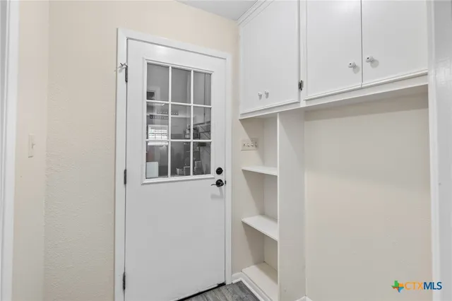 a view of an empty room with cabinet and white cabinet door