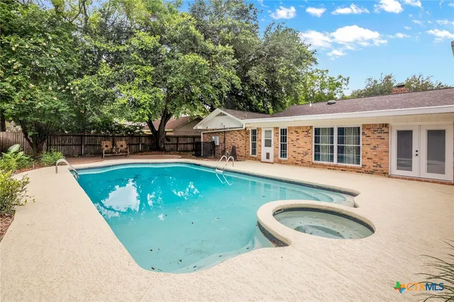an aerial view of a house with swimming pool and large trees