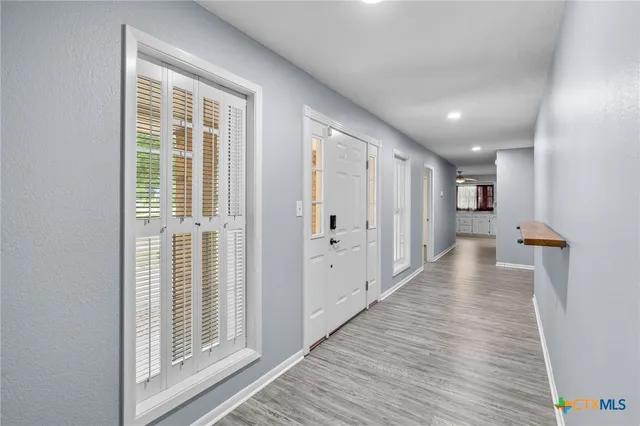 a view of a hallway with wooden floor and windows