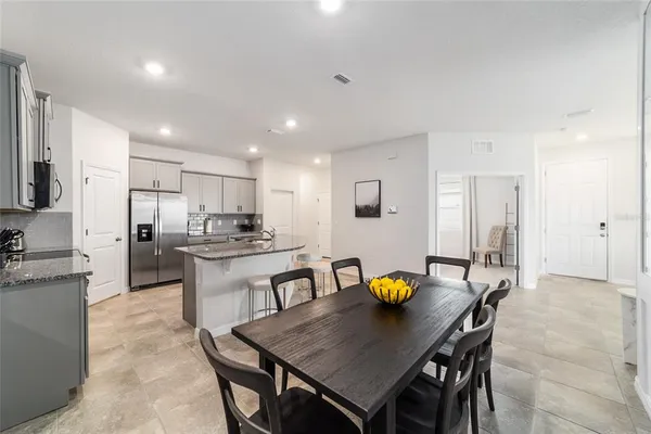 a open dining room with stainless steel appliances a dining table and chairs