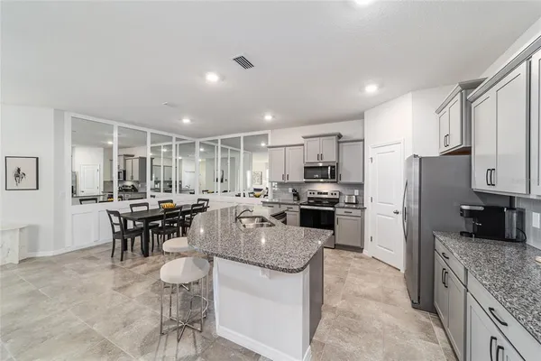 a kitchen with stainless steel appliances granite countertop a refrigerator a stove a sink a dining table and chairs