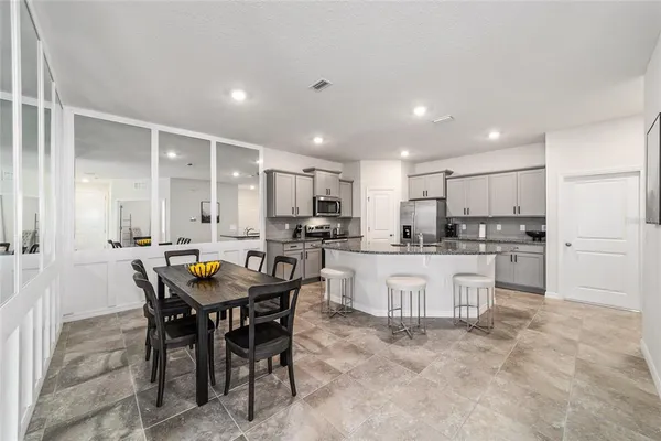 a kitchen with white cabinets and chairs