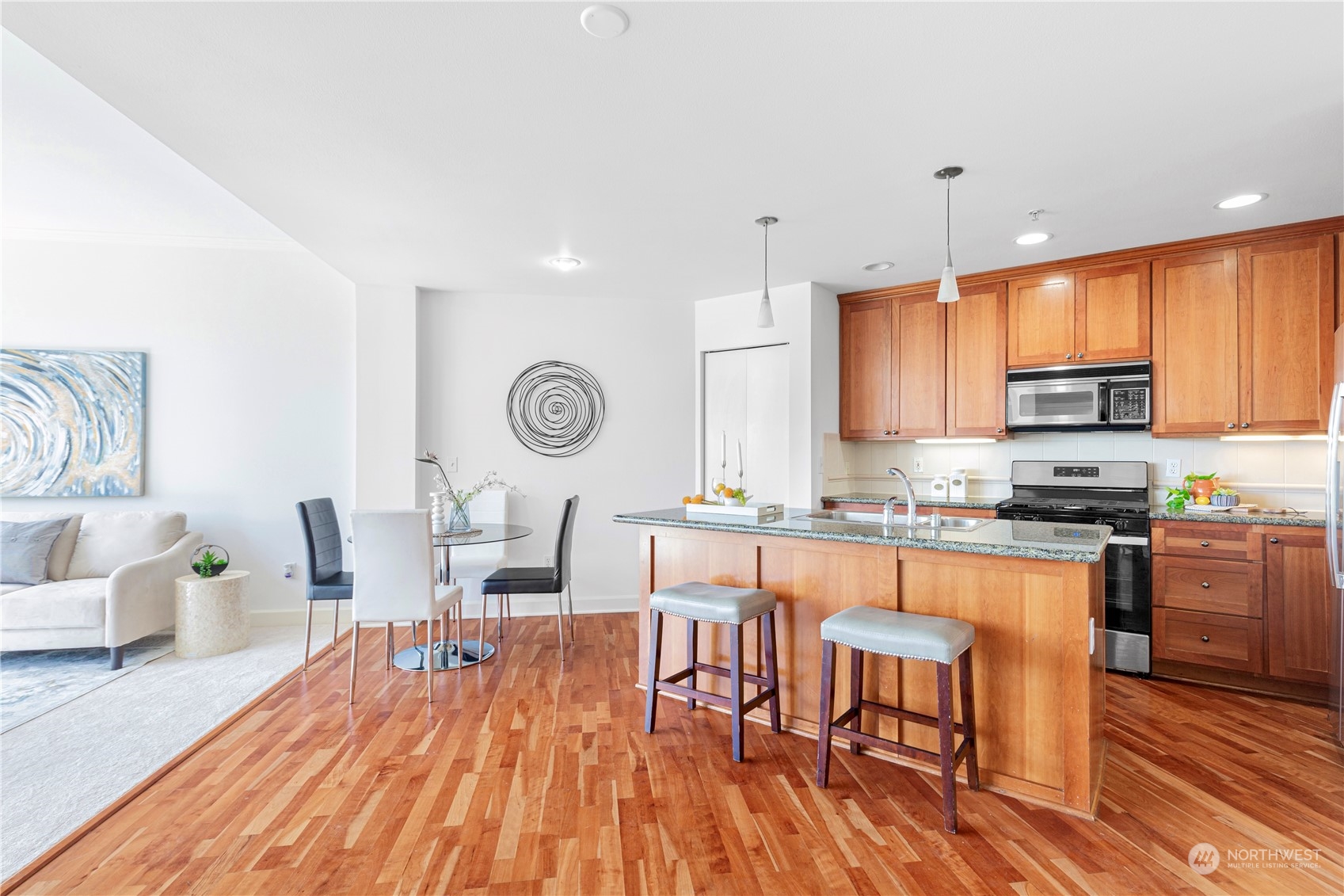 5000 30th Avenue Northeast, Unit 302 Seattle, WA 98105 - Photo 6 of 21 a kitchen with stainless steel appliances granite countertop a stove top oven a sink dishwasher a dining table and chairs with wooden floor