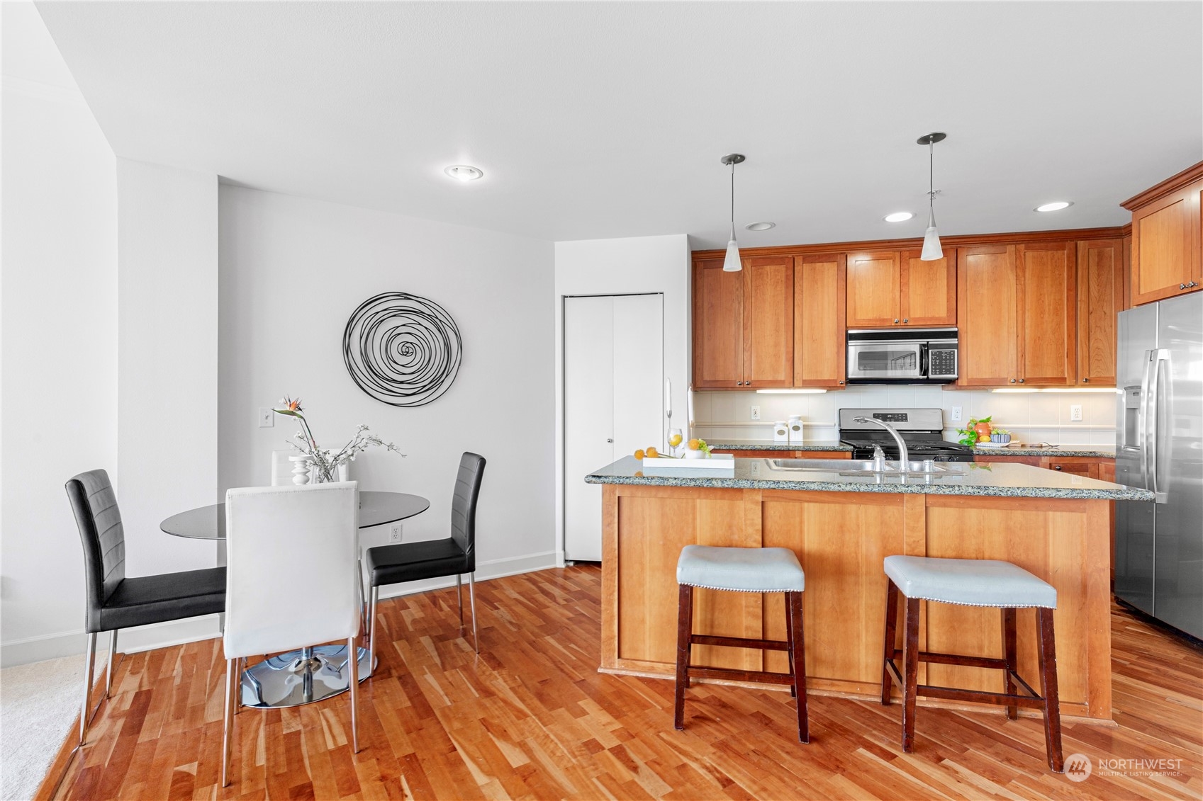 5000 30th Avenue Northeast, Unit 302 Seattle, WA 98105 - Photo 7 of 21 a kitchen with granite countertop wooden floor cabinets a dining table and chairs