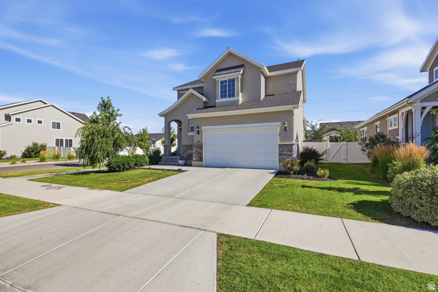 3244 West 1670th Street North Provo, UT 84601 - Photo 3 of 56 Two-story stucco and stone facade residence featuring a two-car garage, concrete driveway, and a manicured lawn with mature landscaping