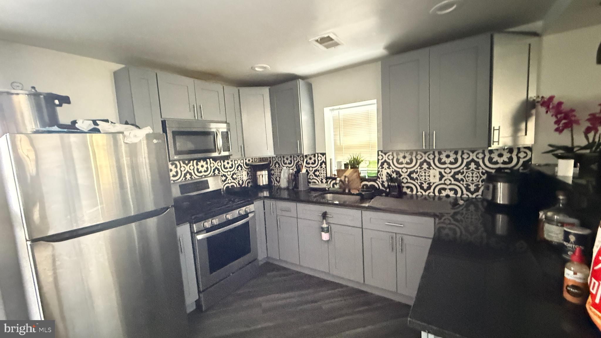 5129 Wakefield Street Philadelphia, PA 19144 - Photo 3 of 17 a kitchen with stainless steel appliances a refrigerator a sink a stove a dining table and chairs