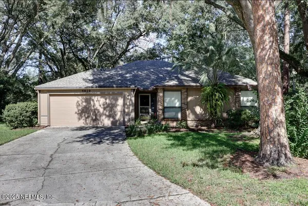 a front view of a house with a garden and trees