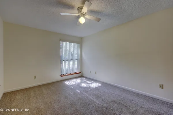 an empty room with a ceiling fan and a window