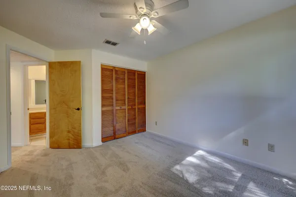 a view of an empty room with chandelier fan and a window