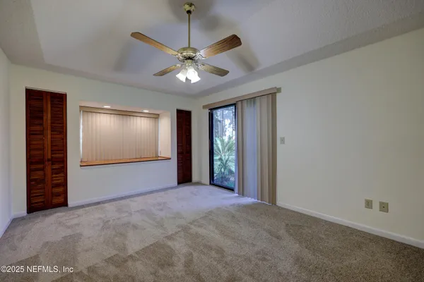 an empty room with a chandelier fan and closet