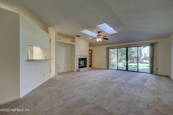 an empty room with chandelier fan and windows