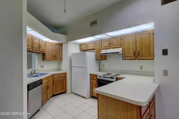 a kitchen that has a sink stainless steel appliances wooden floor and cabinets