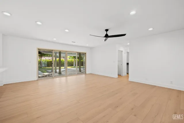 a view of empty room with wooden floor and ceiling fan