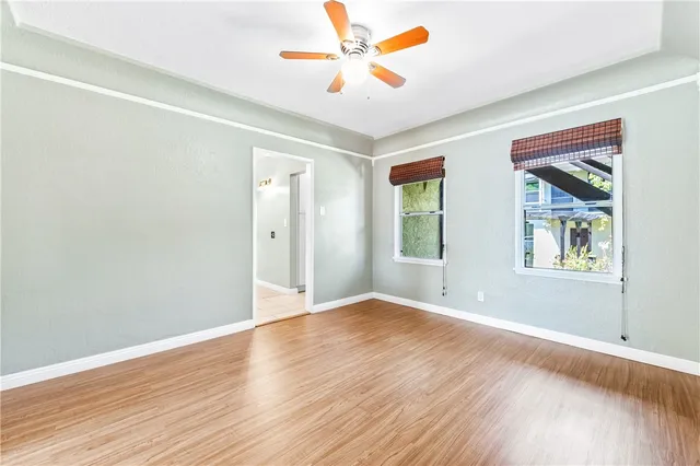a view of an empty room with window and wooden floor