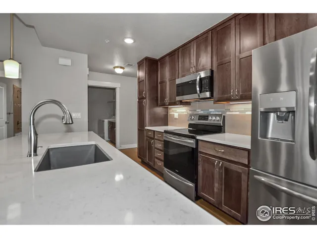 a kitchen with stainless steel appliances wooden cabinets a sink and a refrigerator