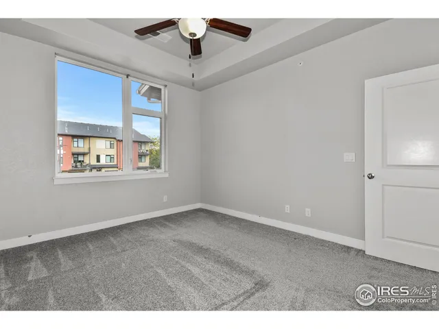 an empty room with windows and ceiling fan