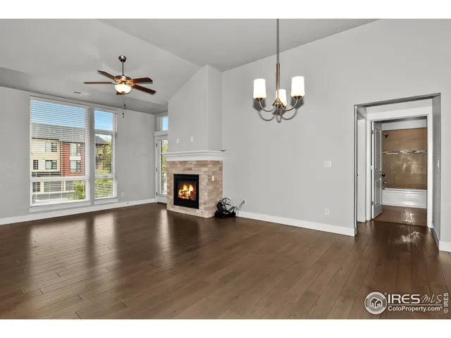 a view of a livingroom with wooden floor a ceiling fan and windows