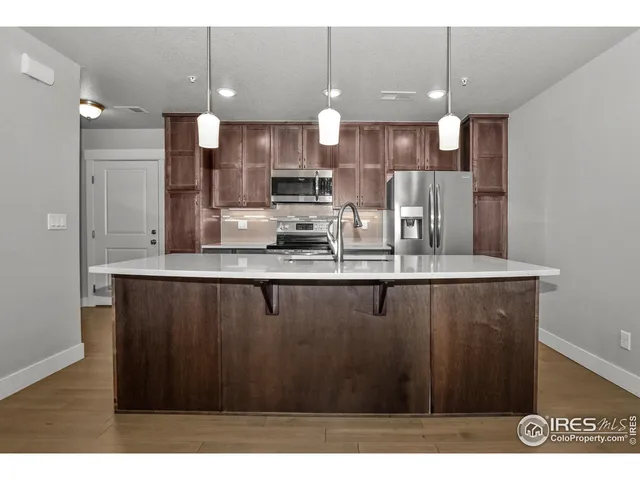 a kitchen with stainless steel appliances kitchen island granite countertop a refrigerator a sink a stove and a wooden cabinets