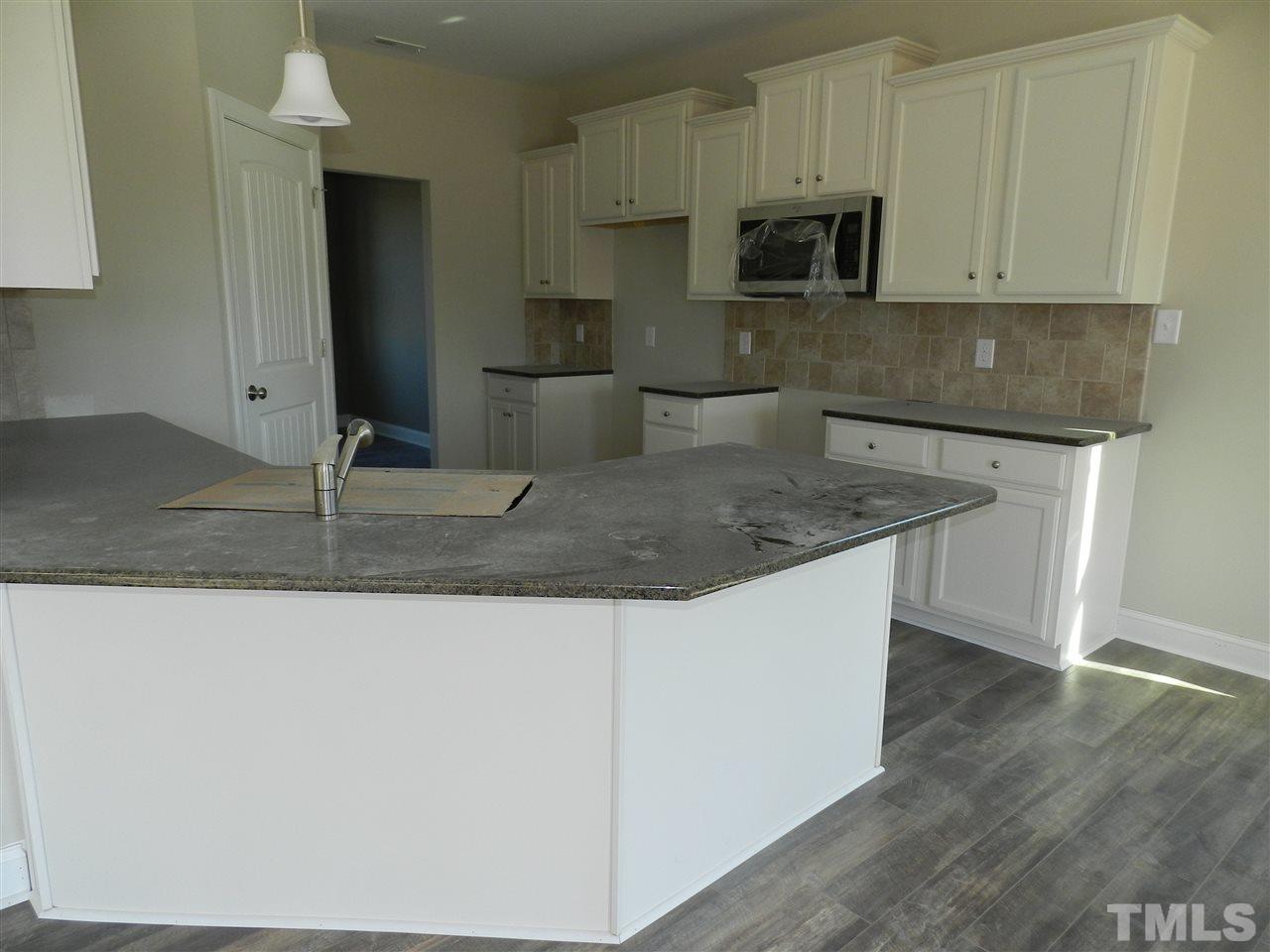19 Labradoodle Court Garner, NC 27529 - Photo 5 of 9 a kitchen with kitchen island granite countertop a sink a stove a microwave and wooden cabinets