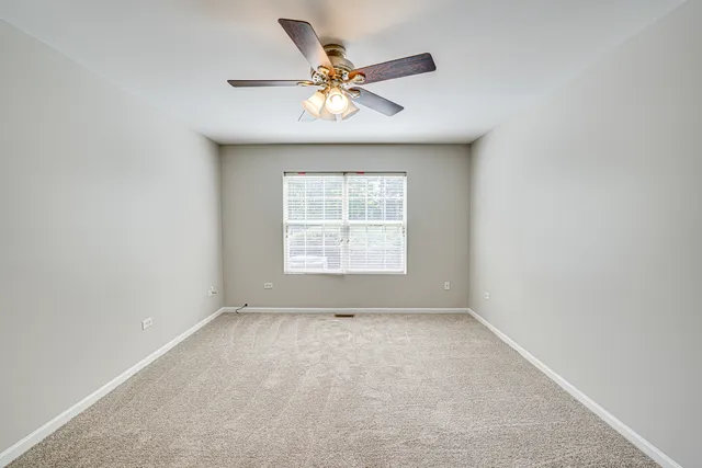 an empty room with a window and a ceiling fan