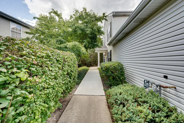 a view of a pathway with side of house next to a yard
