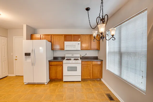 a kitchen with stainless steel appliances granite countertop a refrigerator a sink and white cabinets