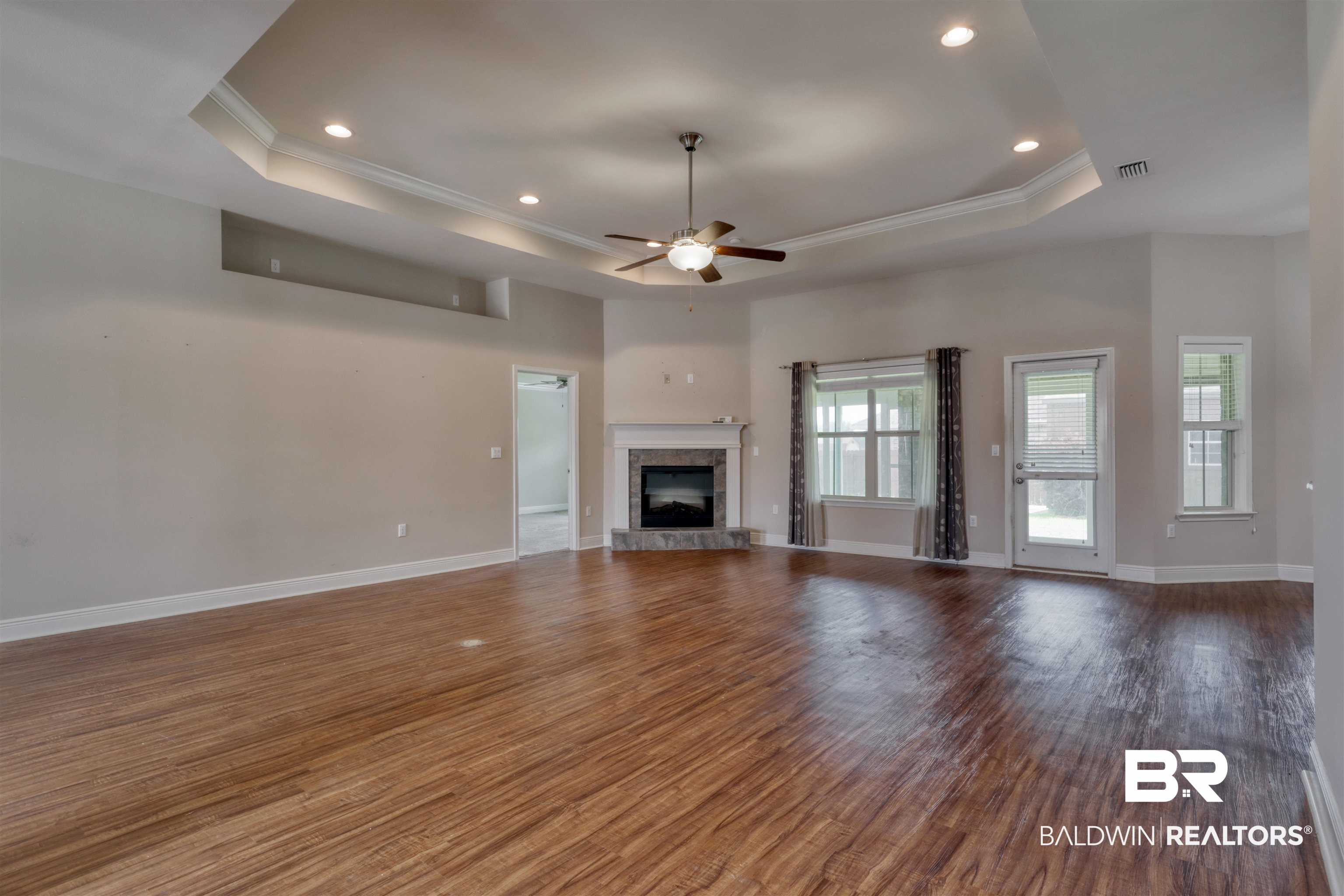 14794 Troon Drive Foley, AL 36535 - Photo 6 of 33 Unfurnished living room with ornamental molding, a raised ceiling, a ceiling fan, and wood finished floors