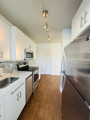 a kitchen with cabinets wooden floor and stainless steel appliances