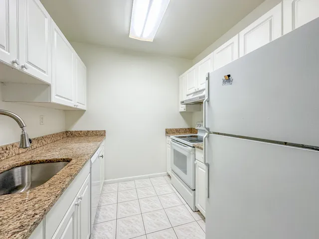 a kitchen with granite countertop a sink stove and refrigerator