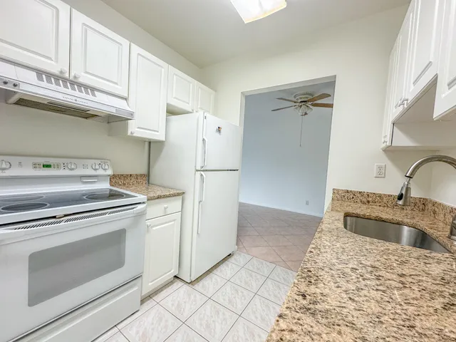 a kitchen with granite countertop a sink stove and refrigerator