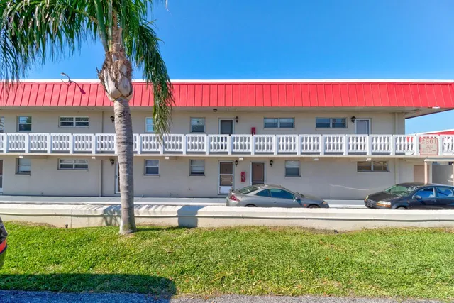 a view of a swimming pool with a lawn chairs and palm trees
