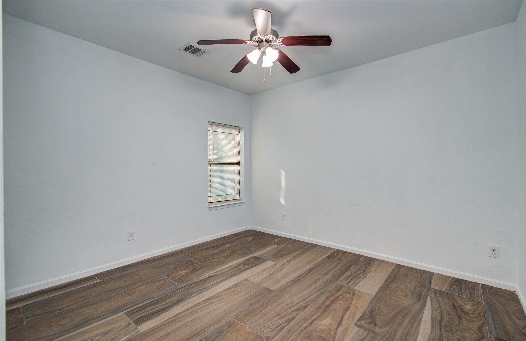 8040 Howton Street, Unit 12 Houston, TX 77028 - Photo 17 of 35 a view of a room with wooden floor chandelier fan and windows