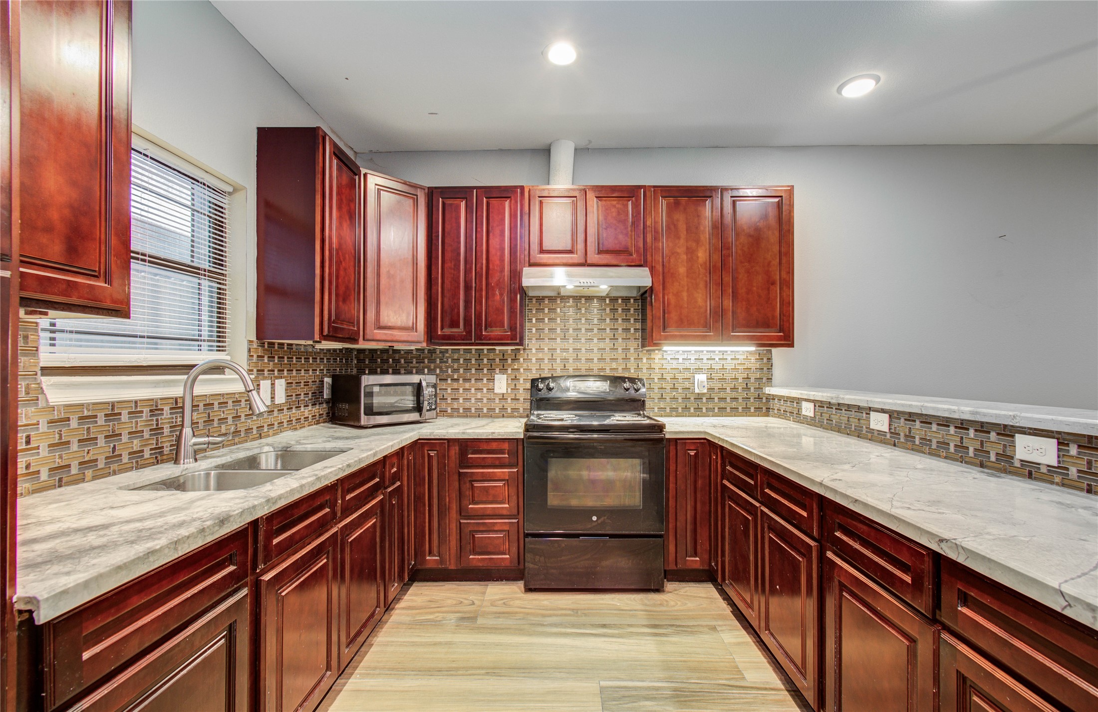 8040 Howton Street, Unit 12 Houston, TX 77028 - Photo 9 of 35 a kitchen with stainless steel appliances granite countertop wooden cabinets a sink and dishwasher a stove top oven with wooden floor