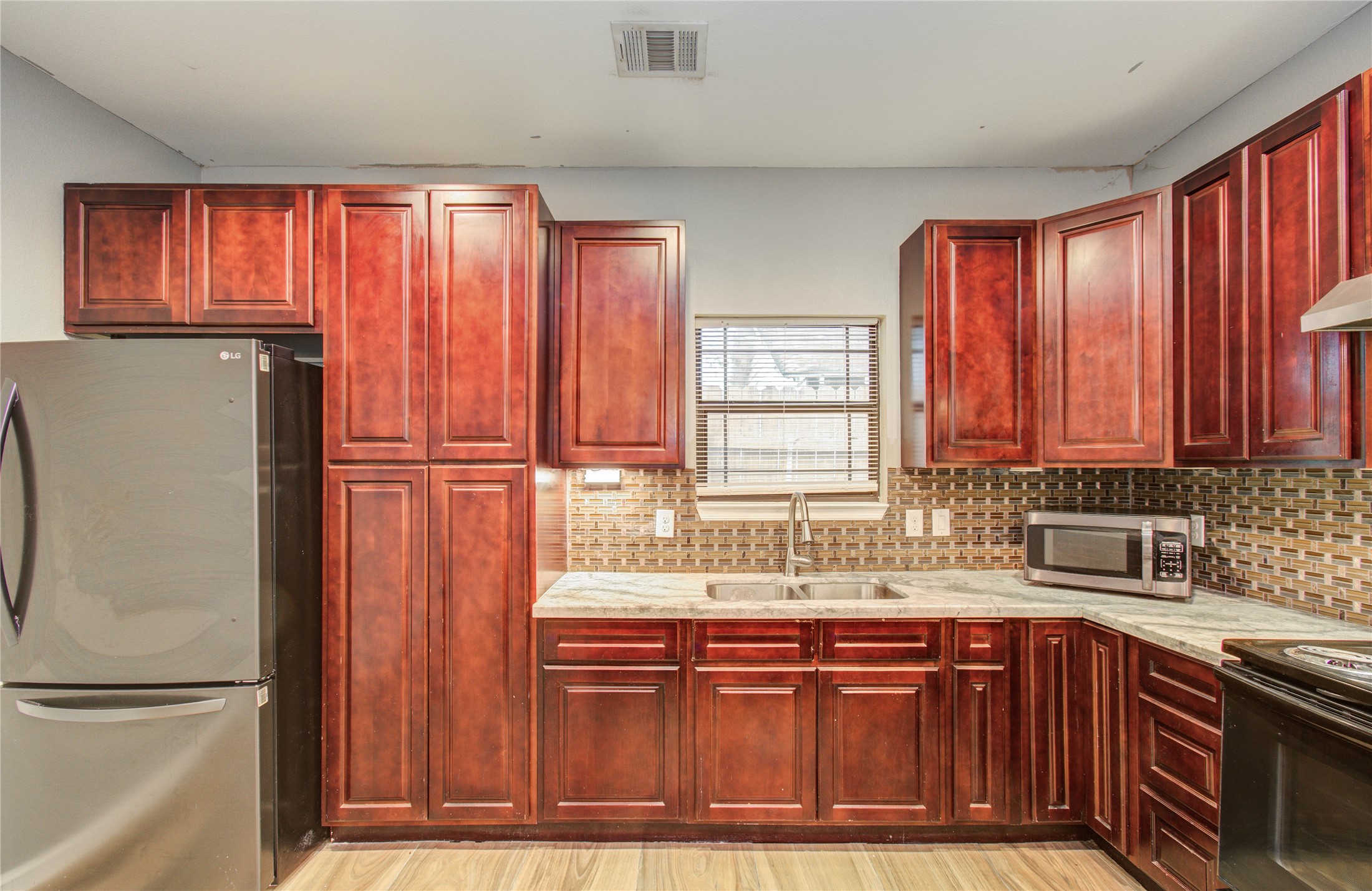 8040 Howton Street, Unit 12 Houston, TX 77028 - Photo 10 of 35 a kitchen with stainless steel appliances granite countertop wooden cabinets a sink and a large window