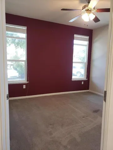 an empty room with windows and fan