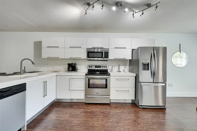 a kitchen with granite countertop a refrigerator stove and sink